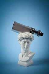 Antique bust of David with vaping device on a blue background. Minimal still life