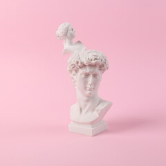 Antique Plaster busts of David and Venus on pink background. Conceptual pop. Minimal still life photography
