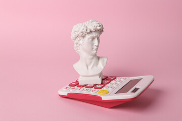 Antique David bust with calculator on pink background. Conceptual pop. Minimal still life. Creative...