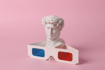 Antique bust of David with 3d glasses on pink background. Conceptual pop. Minimal still life....