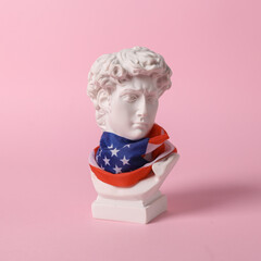 David bust with usa flag on his face against a pink background. Patriotism. Minimal still life