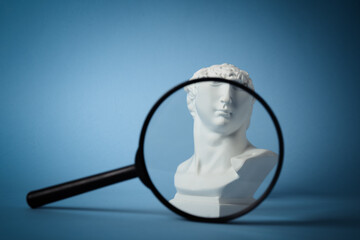 David's bust through magnifying glass on blue background