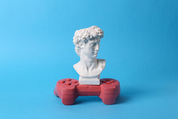 Antique David bust with gamepad on blue background. Gaming. Conceptual pop. Minimal still life. © splitov27