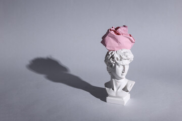Antique David bust with crumpled paper ball on gray background. Conceptual pop. Minimal still life. Creative idea