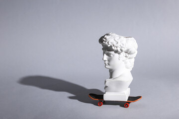 David bust on a skateboard. Gray background. Minimal still life