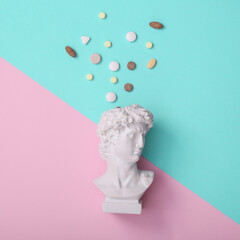 David bust with pills on pink blue background. Creative layout. Minimal still life. Flat lay. Top view
