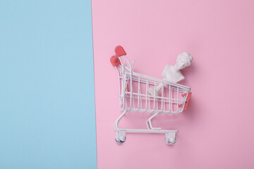 Shopping trolley with venus bust on pink blue background. Creative layout. Minimal shopping still...
