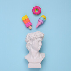 David bust with ice cream and donut on a blue background. Minimal still life