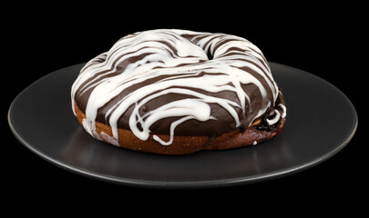 bun covered with chocolate, in a dark plate on a black background