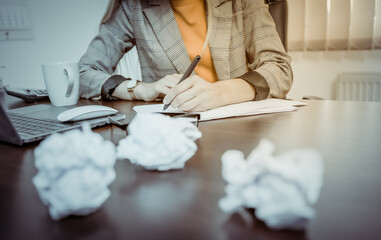 Woman boss with crumpled paper balls in her office