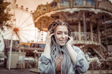 Extraordinary woman with African braids and flamboyant makeup spends time in an amusement park
