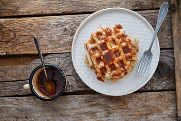 Waffles with caramel sauce. Wooden background. Top view. 