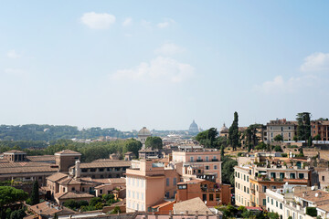 Fototapeta na wymiar View of the city of Rome on a beautiful summer day. Cityscape with architecture and old buildings. Far away in the skyline the church St. Peter's Basilica can be seen. Photo taken in Rome, Italy.