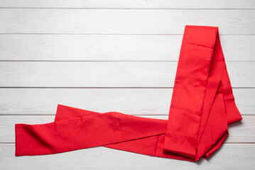 Red waistband from the Kimono on the white wooden table flat lay background with copy space.
