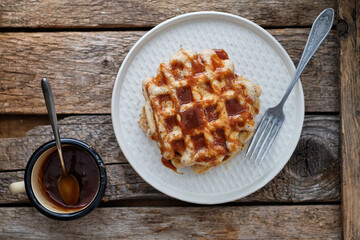Waffles with caramel sauce. Wooden background. Top view. 