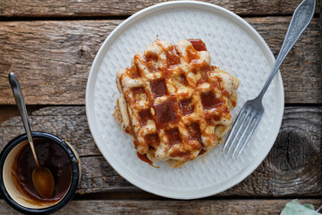 Waffles with caramel sauce. Wooden background. Top view. 