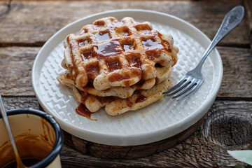 Waffles with caramel sauce. Wooden background. Top view. 