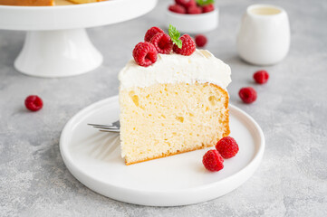Tres leches cake with whipped cream and fresh raspberries on top of a gray concrete background....