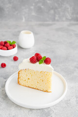Tres leches cake with whipped cream and fresh raspberries on top of a gray concrete background. Traditional cake from Latin America. Copy space.