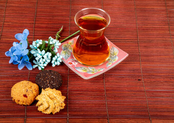 Delicious fresh morning black tea with cookies and flower around isolated on a wooden background. Space for text.