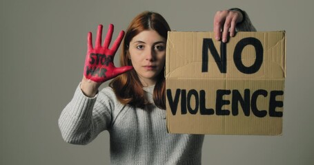 Girl raises the sign that says no violence and the hand with stop war in protest