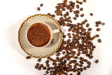 Cup of black coffee with scattered roasted coffee beans on white table. frothy coffee concept