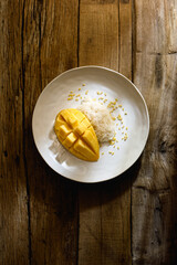 Top view of Mango Sticky Rice, Southeast Asian dessert plate on wooden table top