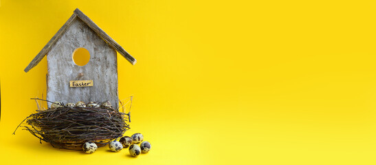 Decorative Easter birdhouse on a yellow background. A nest with quail eggs. Easter card. Spring...