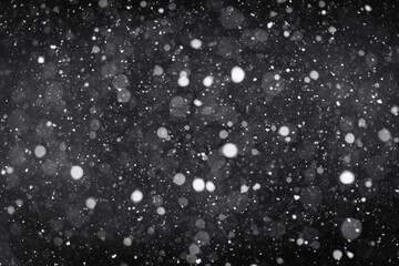 Snow is falling on the street at night.