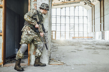 Military in the form holds in the hands a big rifle,  looks opponents from the corner.