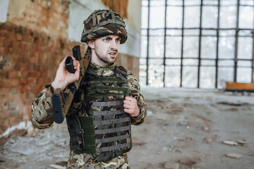Male soldier in uniform with gun in his hands. Portrait of a man in destroy building.