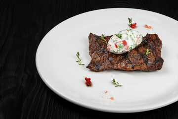 Grilled juicy marinated beef outside skirt steak on a plate with cream and vegetable