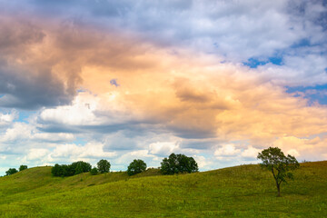 Colored beautiful clouds and a green glade.