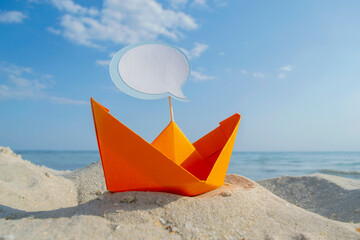 Orange Paper Boat on Sandy Seashore Close-up. Small Paper Boat on Background of Blue Sea on Sunny...