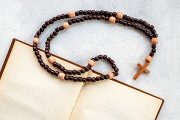 Old Bible book with wooden christian rosary beads