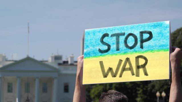A man holds a STOP WAR Ukraine protest sign outside the White House.  