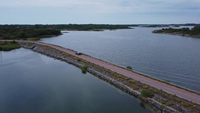 Car driving on a narrow bridge in Brando Island in Aland Islands, Finland, aerial spotlight shot