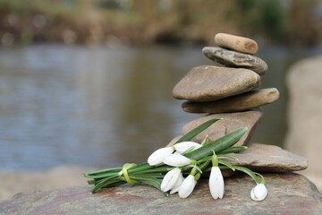 Fototapeta premium Balancepyramide mit Schneeglöckchen am Fluss