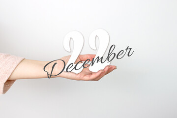 December 22nd. Day 22 of month, Calendar date. Calendar Date floating over female hand on grey background. Winter month, day of the year concept.