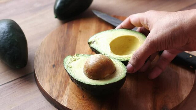 women hand cutting slice of avocado with knife, 