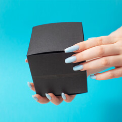 female hand  with black gift box  on blue background