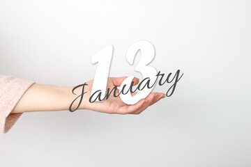 January 13rd. Day 13 of month, Calendar date. Calendar Date floating over female hand on grey background. Winter month, day of the year concept.