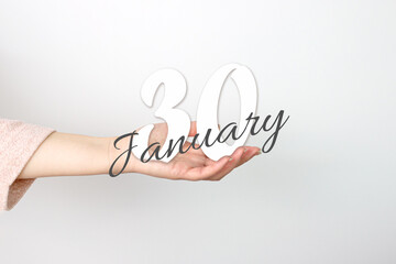 January 30th. Day 30 of month, Calendar date. Calendar Date floating over female hand on grey background. Winter month, day of the year concept.