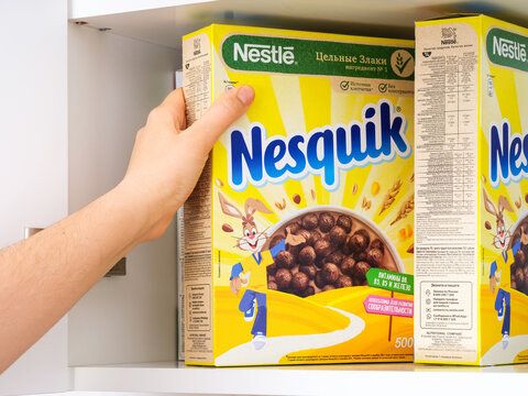 Tambov, Russian Federation - February 19, 2022 Woman hand taking Nestle Chocolate Nesquik cereal box out of a cupboard