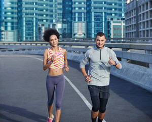 We love a bit of competition. Shot of two friends jogging together through the city streets.