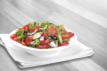 Healthy salad bowl with different lettuce, chicken, cheese on the table in restaurant.