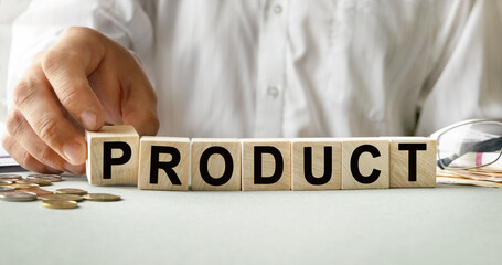 PRODUCT inscription on the texture of wooden cubes. A business man holds a cube in his hand. An inscription on a financial, business or economic theme.