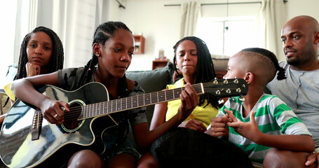 Casual black African family bonding thogether through music guitar. Daughter playing musical instrument