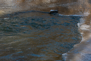 A washout in the ice, on a fast mountain river. A fast mountain river, broke through ice, snow and formed a washout.