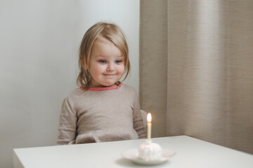 Cute beautiful little baby girl celebrating birthday. Child blowing one candle on a cake. Birthday family party for lovely toddler child, beautiful daughter